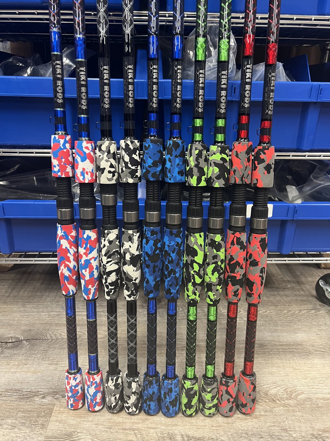 Rods standing in a shop rack, their grips wrapped in five camouflage patterns: red white and blue, black and white, blue, green, and red