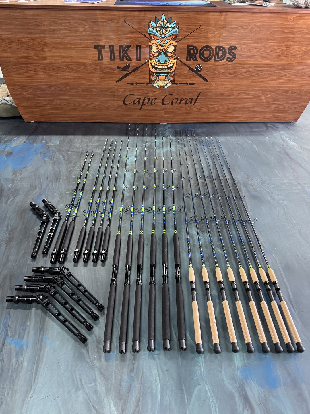 A carved Tiki Rods Cape Coral sign above a full set of finished rods laid out across the marbled bench
