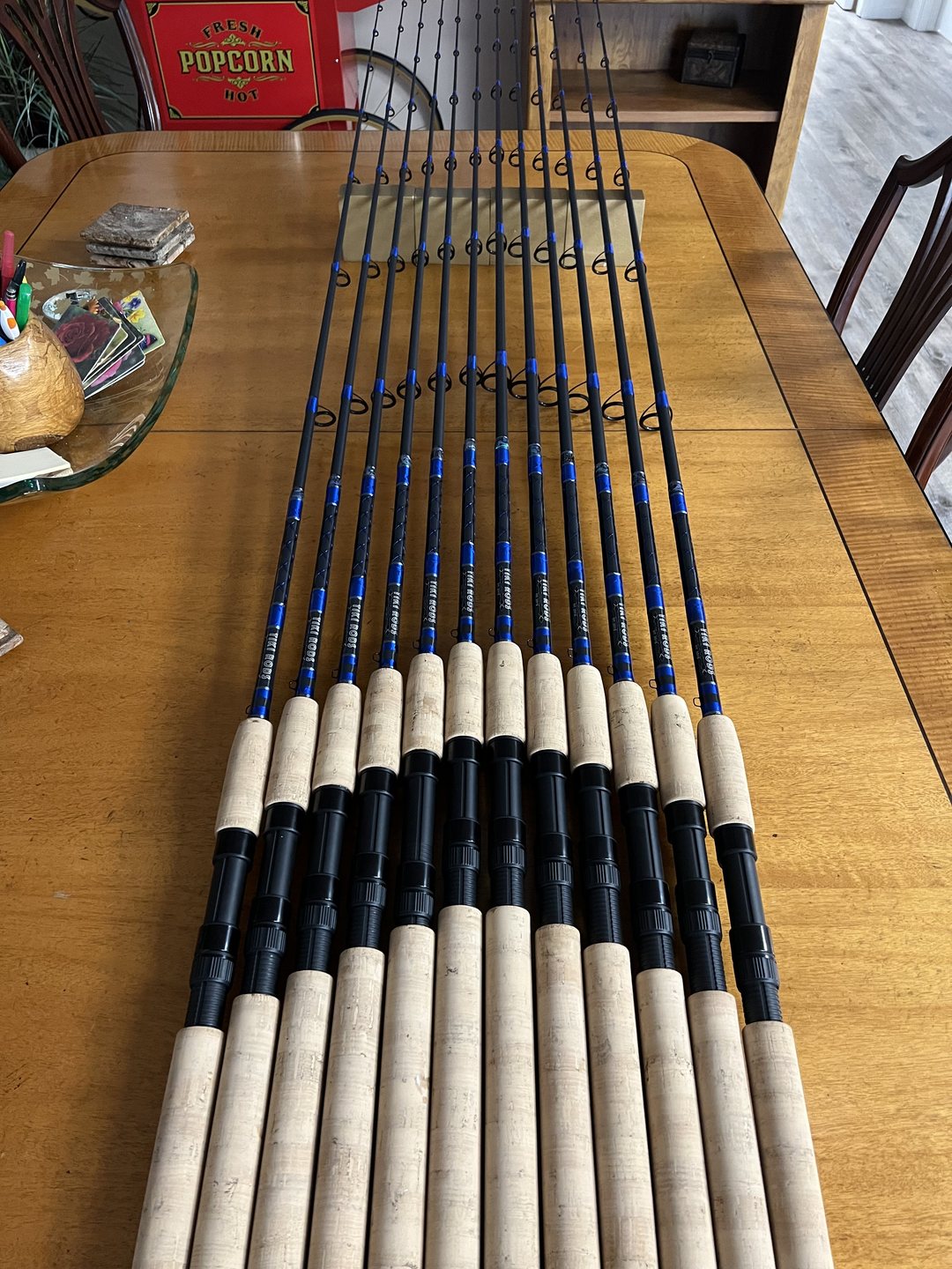 A long row of blue-wrapped rods with cork and black grips laid across the shop table